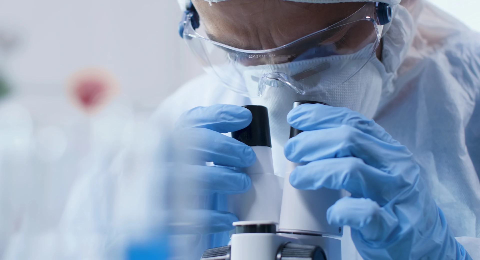 Rentokil Initial scientist looks at a specimen under a microscope