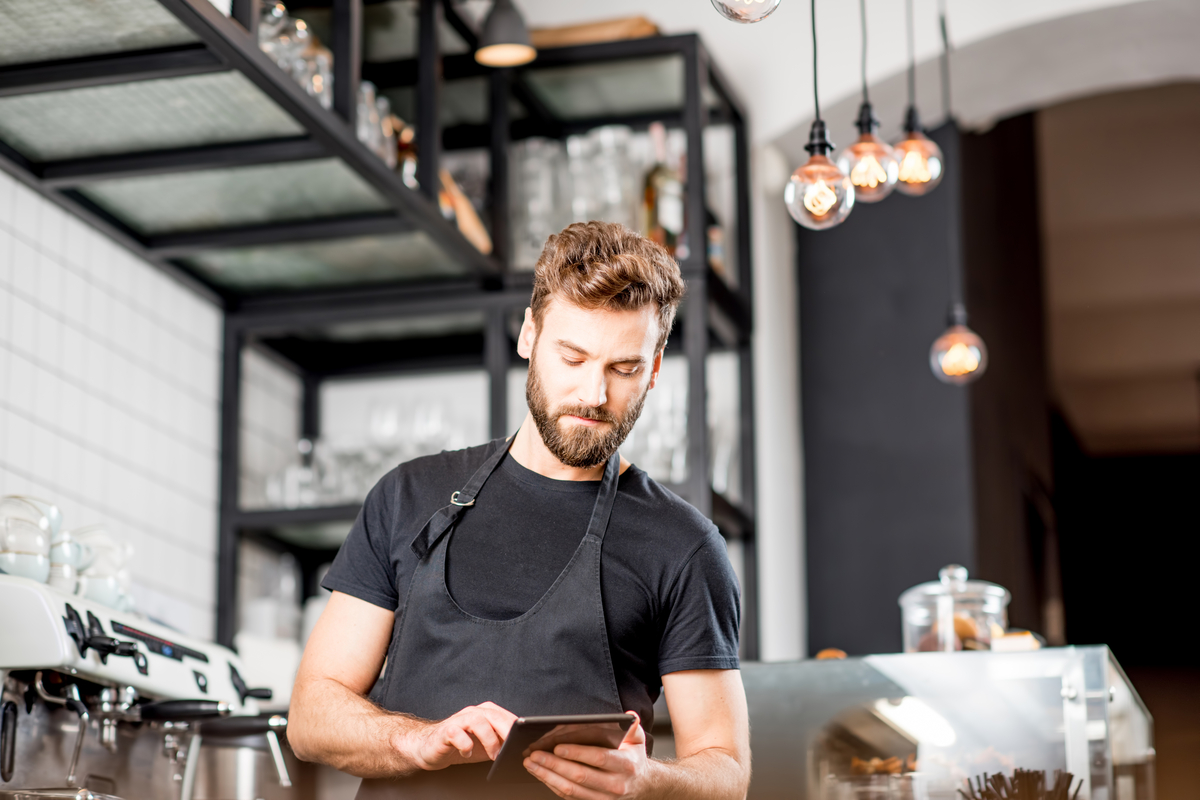 Waiter in a restaurant serving customers with ipad