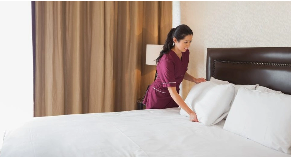 housekeeper making hotel bed